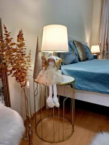 a lamp with a doll on a table next to a bed at Albina apartman in Eger