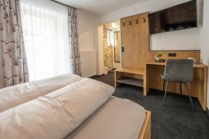 a bedroom with a bed and a desk and a television at Vermunt - Silvretta Premium Card von Juli bis September in Galtür