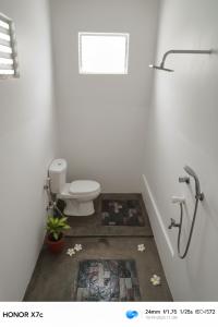 een witte badkamer met een toilet en een tapijt bij Almond Breeze Cottage in Udawalawe