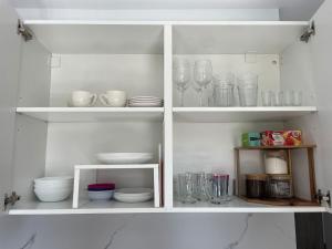 een witte kast gevuld met borden en glazen bij Zacisze Ludowa in Olecko