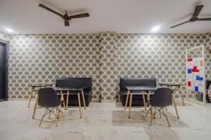 a room with two tables and chairs in front of a wall at Collection O MG Guest House in Kolkata