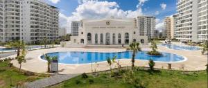 a building with a large swimming pool in front of buildings at THE PALMiA I iskele I Trikomo in Aglantzia