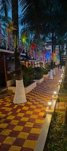 a sidewalk with palm trees and lights on it at Maitree Beach Resort in Arambol