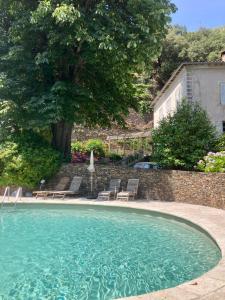 een groot zwembad met stoelen en een huis bij Gîte Le COCON au Clarou in Valleraugue