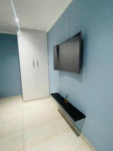 a room with a tv on a blue wall with a floor at RT Guest House in Walvis Bay