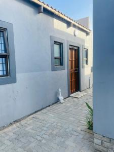 a white house with a door and a stone driveway at RT Guest House in Walvis Bay
