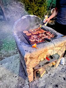 Iemand grilt vlees op een stenen grill. bij Eden Natural Resort - Transalpina in Căpîlna +58 foto's