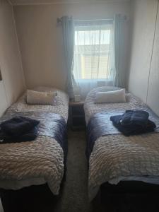 two beds in a small room with a window at The Suite in Tosside