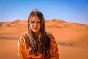 een vrouw in het zand in de woestijn bij Merzouga Infinity Dunes Camp in Merzouga