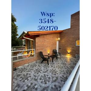 eine Terrasse mit zwei Stühlen und einer Uhr an einem Gebäude in der Unterkunft Don Hugo in Villa Giardino