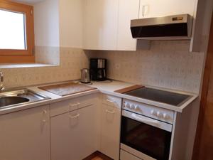 a kitchen with white cabinets and a sink and a stove at Fuldera Daint chasa Zanoli Wohnung Parterre in Fuldera