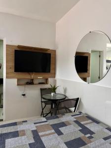 un soggiorno con TV, tavolo e specchio di Porto dos Lençóis, Apartamento 05 a Barreirinhas