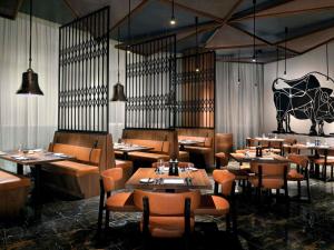 een restaurant met tafels en stoelen in een kamer bij Mövenpick Hotel & Apartments Ghala Muscat in Muscat