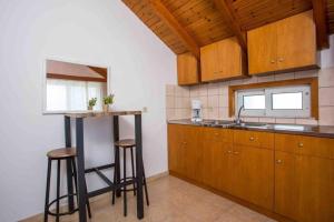 una cucina con armadi in legno, lavandino e sgabelli di MEGAT SEAVIEW AND SEASIDE APARTMENTs a Ialyssos