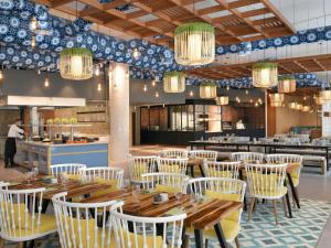 Un restaurante con mesas de madera y sillas blancas. en Mövenpick Hotel & Apartments Ghala Muscat, en Mascate