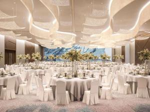 Un salón de banquetes con mesas y sillas blancas. en Mövenpick Hotel & Apartments Ghala Muscat, en Mascate 195 fotos más