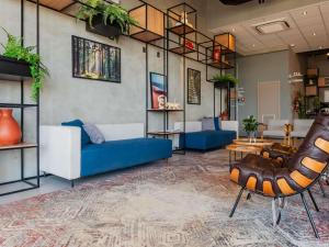 Una sala de estar con un sofá azul y sillas. en ibis Lavras, en Lavras
