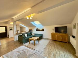 a living room with a green couch and a television at Gästehaus Florian in Grainau
