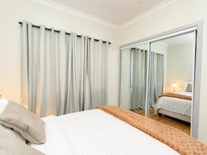 una camera da letto con due letti e uno specchio di Hunter Valley Modern 4-Bedroom House a North Rothbury