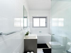 un bagno bianco con vasca, WC e lavandino di Hunter Valley Modern 4-Bedroom House a North Rothbury Altre 28 foto