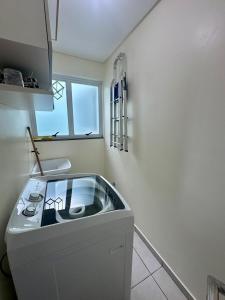 eine weiße Küche mit Spüle und Fenster in der Unterkunft Ótima Localização!!! Apartamento De Frente No Centro De Capão Da Canoa in Capão da Canoa