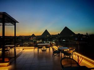 a patio with tables and chairs on a balcony with pyramids at Pyramids Spiritual Gate in Cairo