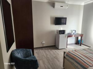 een kamer met een bed, een stoel en een televisie bij Pado B & B in Gqeberha