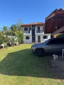 a car parked in front of a house with a dog at Casa de praia Silva Bráz in Serra
