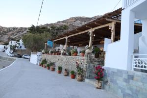 a building with potted plants on a brick wall at TO VOTSALO-beach side studios & taverna in Karpathos +38 photos