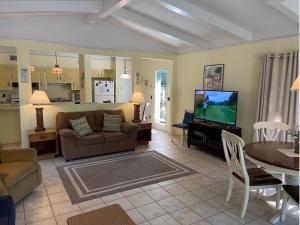 een woonkamer met een bank, een tafel en een tv bij Sea Cottage Apartment in Jekyll Island