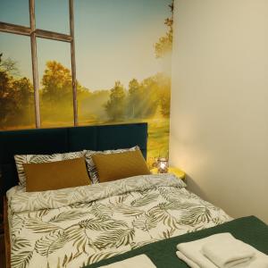 een slaapkamer met een bed met een schilderij aan de muur bij Apartament ZłotogórSKI Lądek-Zdrój in Lądek-Zdrój