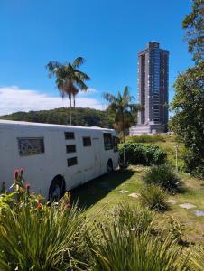 une camionnette blanche garée devant un grand immeuble dans l'établissement Suite Penha SC, à Penha