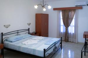 a bedroom with a bed and a dresser and windows at TO VOTSALO-beach side studios & taverna in Karpathos