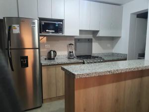 eine Küche mit einem Kühlschrank aus Edelstahl und einer Mikrowelle in der Unterkunft Departamento Centrico Yanahuara Beaterio in Arequipa