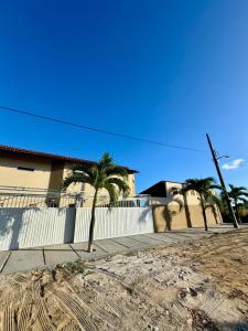 uma rua com palmeiras e uma cerca branca em Flats Varandas Praia Bela - Apto 103 em Pitimbu