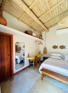 ein Schlafzimmer mit zwei Betten und einem Tisch und einem Spiegel in der Unterkunft Casa Preguiça Corumbau in Corumbau