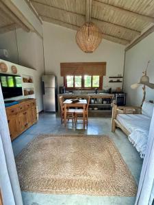 ein Wohnzimmer mit Tisch und Küche in der Unterkunft Casa Preguiça Corumbau in Corumbau