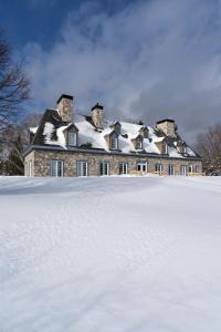 een groot huis met een met sneeuw bedekt dak bij Le Baluchon Éco-villégiature in Saint-Paulin