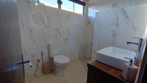 a white bathroom with a toilet and a sink at Villa Loma in Caacupé