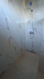 a bathroom with a shower with a white marble wall at Villa Loma in Caacupé +2 photos