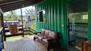 a couch sitting on the porch of a green house at Recanto dos Pássaros in Palhoça