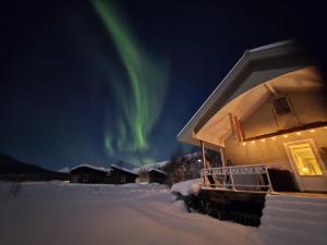 een huis met het noorderlicht in de lucht erachter bij Fjord & Flame in Tromsø