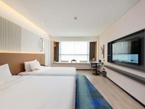 a hotel room with two beds and a flat screen tv at Grand Mercure Guangzhou Baiyun in Huadu +93 photos