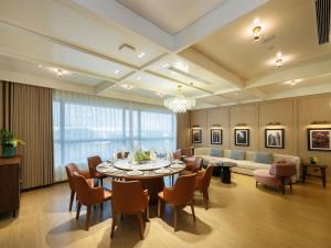 a dining room with a table and chairs and a couch at Grand Mercure Guangzhou Baiyun in Huadu
