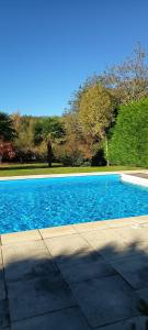 een zwembad met blauw water naast een stoep bij Domaine Le Verger Chambres dhotes de Charme avec Hammam a Saint Estephe in Saint-Estèphe +33 foto's