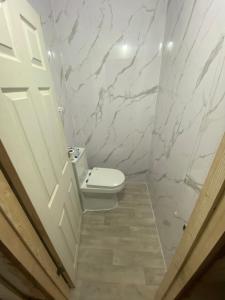 a white bathroom with a toilet and a door at EAST HAM HOME SHARe in London
