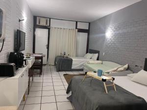 een hotelkamer met twee bedden en een televisie bij Angra dos Reis Flat Suíte no Portogalo in Angra dos Reis