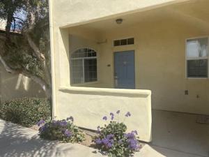 a white house with a blue door and purple flowers at The Mahogany Shore in Oceano