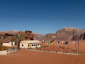a group of flags in front of a building in the desert at Desert Nights Camp in Wadi Rum