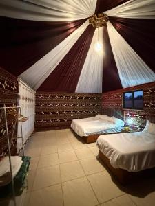 a bedroom with two beds in a room with a ceiling at Desert Nights Camp in Wadi Rum